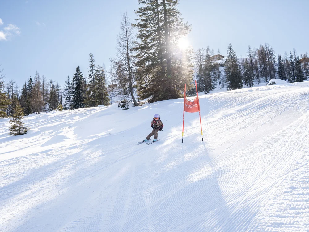Winterurlaub beim Forstauerwirt Skifahrer fährt auf einer verschneiten Piste an einem roten Tor vorbei