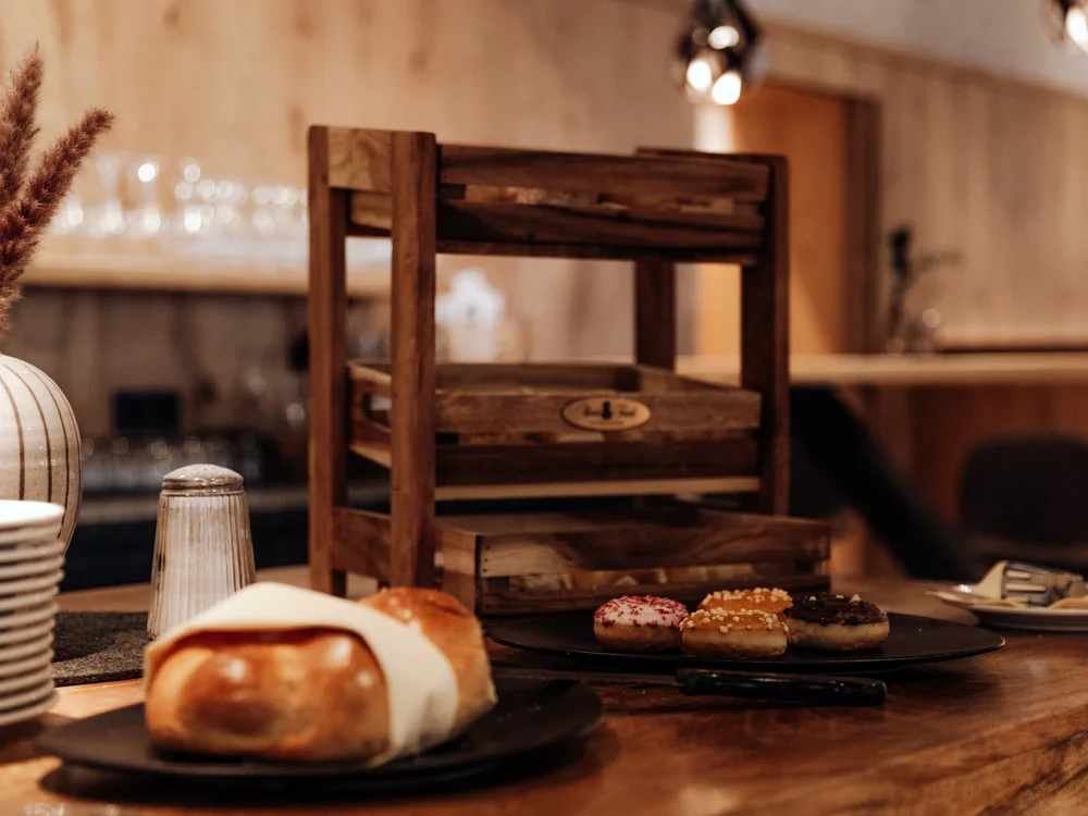 Winterurlaub beim Forstauerwirt Brot und kleine Gebäckstücke auf einem Buffet mit rustikalem Holzregal