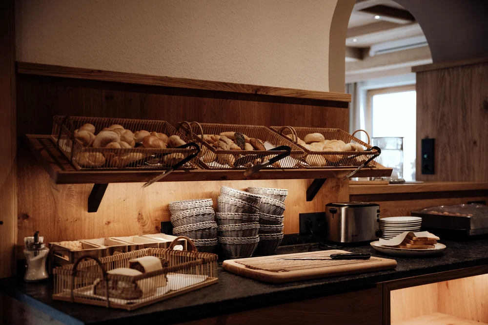 Frühstücksbuffet mit Brotkörben, Körben und einem Toaster auf einer Holztheke