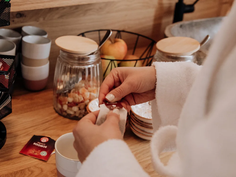 Winter holidays at Forstauerwirt Person in a white bathrobe preparing tea at a beverage station