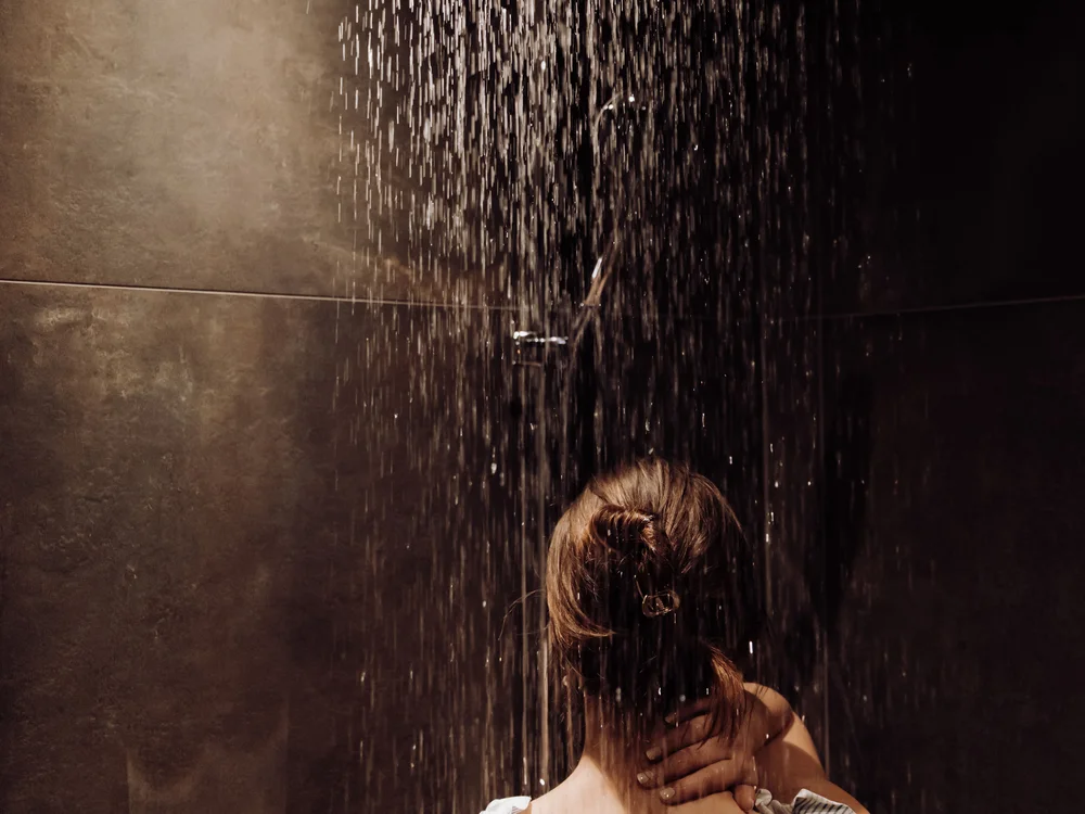 Winterurlaub beim Forstauerwirt Frau steht mit dem Rücken zur Kamera unter einer Regendusche