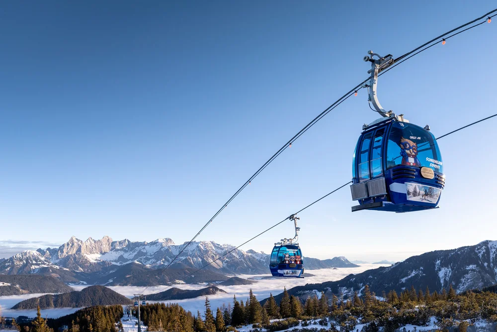 Blaue Gondeln schweben über einer verschneiten Berglandschaft