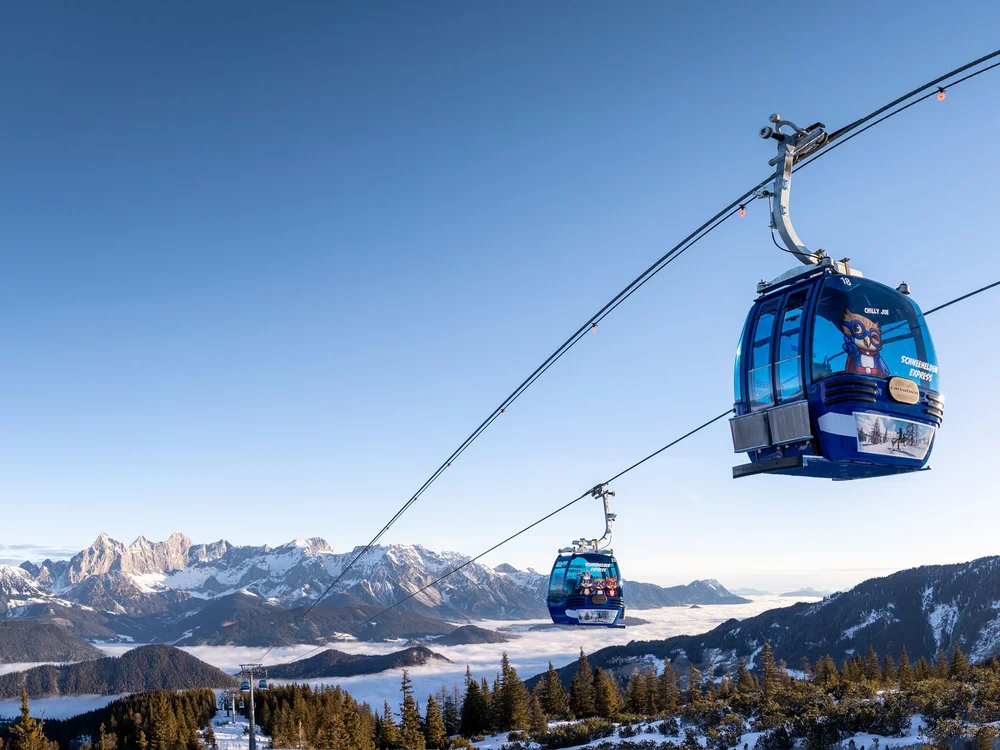 Winterurlaub beim Forstauerwirt Blaue Gondeln schweben über einer verschneiten Berglandschaft