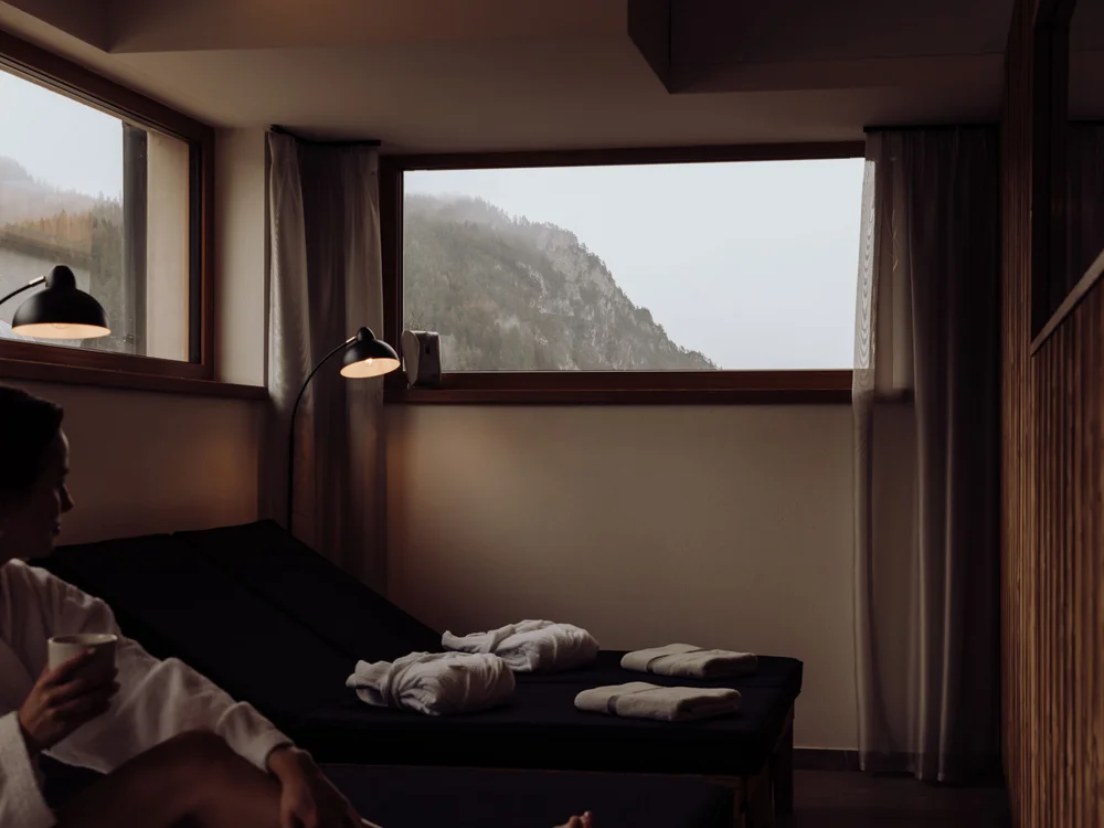 Winterurlaub beim Forstauerwirt Frau im Bademantel auf einer Liege mit Handtüchern und Blick auf einen bewaldeten Berg