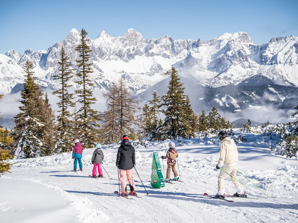 Winterurlaub beim Forstauerwirt Skifahrer auf einer verschneiten Piste vor schneebedeckten Bergen