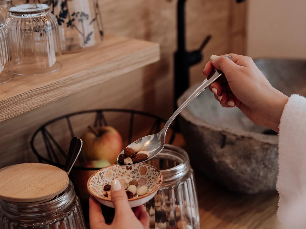 Winterurlaub beim Forstauerwirt Hände füllen Nüsse und Trockenfrüchte aus einem Glas in eine gemusterte Schale
