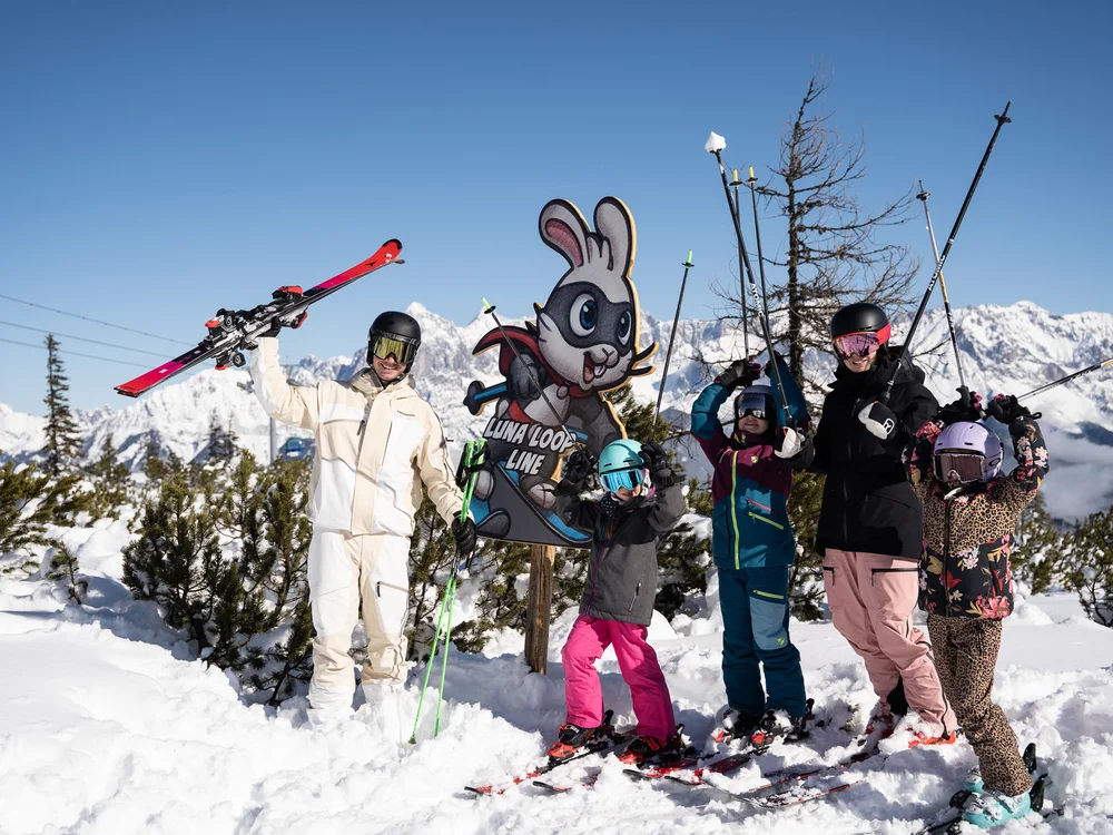 Winterurlaub beim Forstauerwirt Eine Gruppe Skifahrer posiert im Schnee vor einem Hasenschild und schneebedeckten Bergen