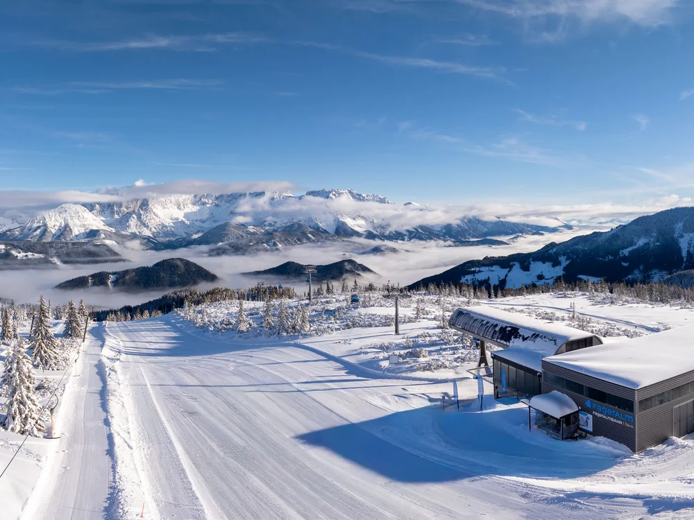 Winterurlaub beim Forstauerwirt Verschneite Skipiste mit Liftstation vor einem Bergpanorama