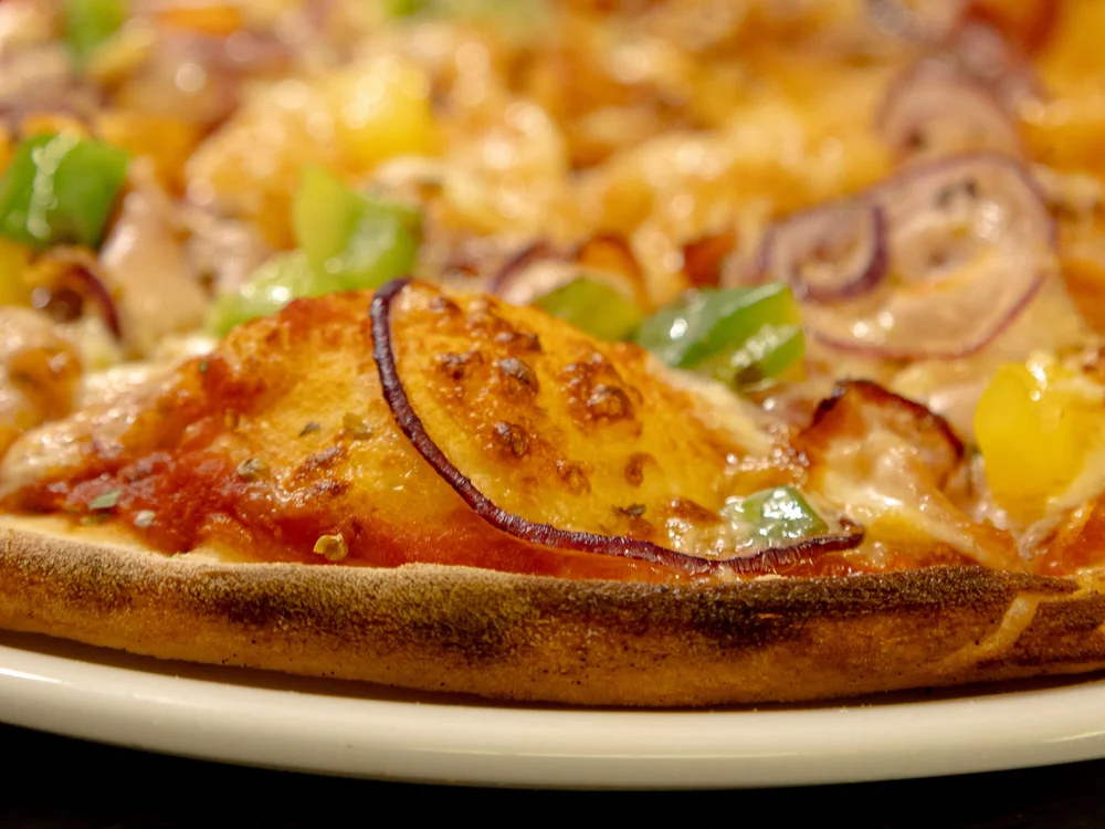 Winterurlaub beim Forstauerwirt Nahaufnahme einer Pizza mit Käse, Paprika, Zwiebeln und Pilzen
