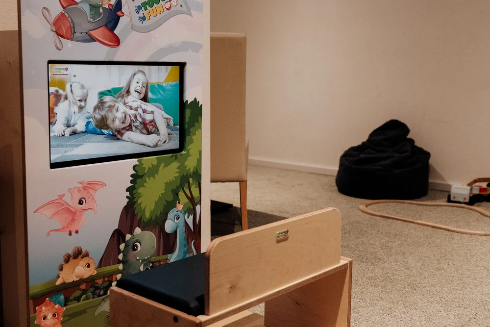 Kinderspielbereich mit bemaltem Bildschirm, Holzbank und schwarzem Sitzsack