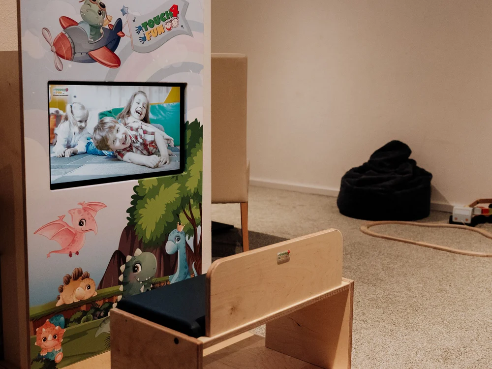 Winterurlaub beim Forstauerwirt Kinderspielbereich mit bemaltem Bildschirm, Holzbank und schwarzem Sitzsack