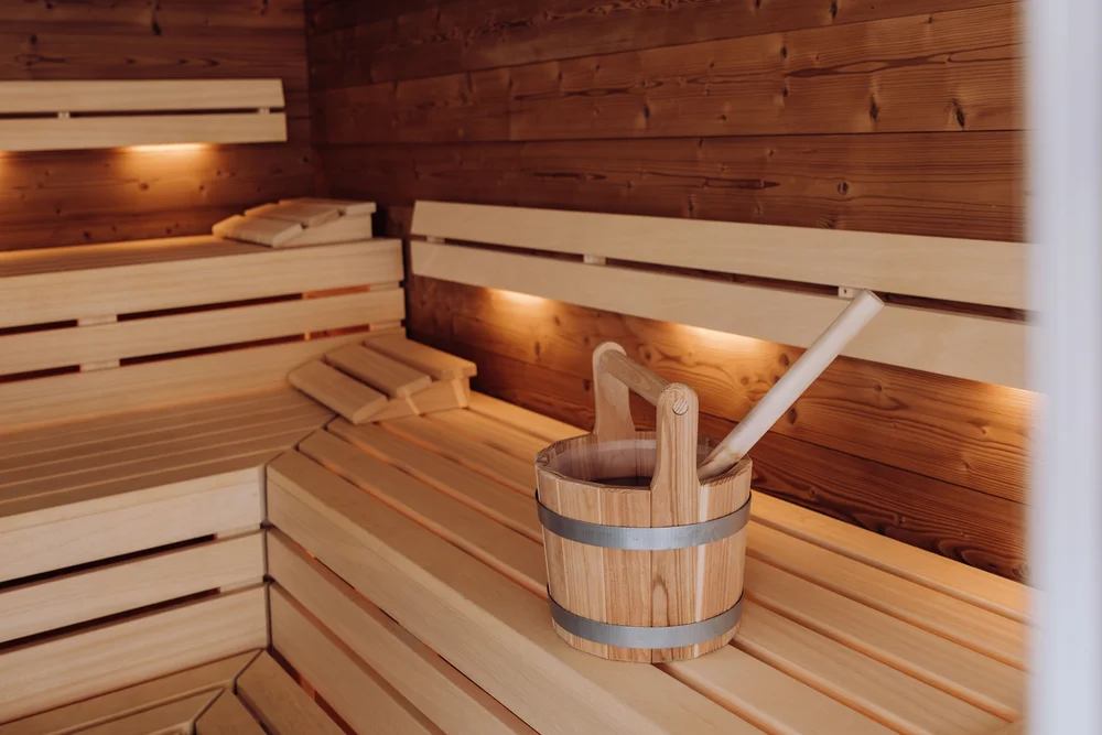 Holzsauna mit Sitzbänken und einem Holzeimer mit Schöpfkelle