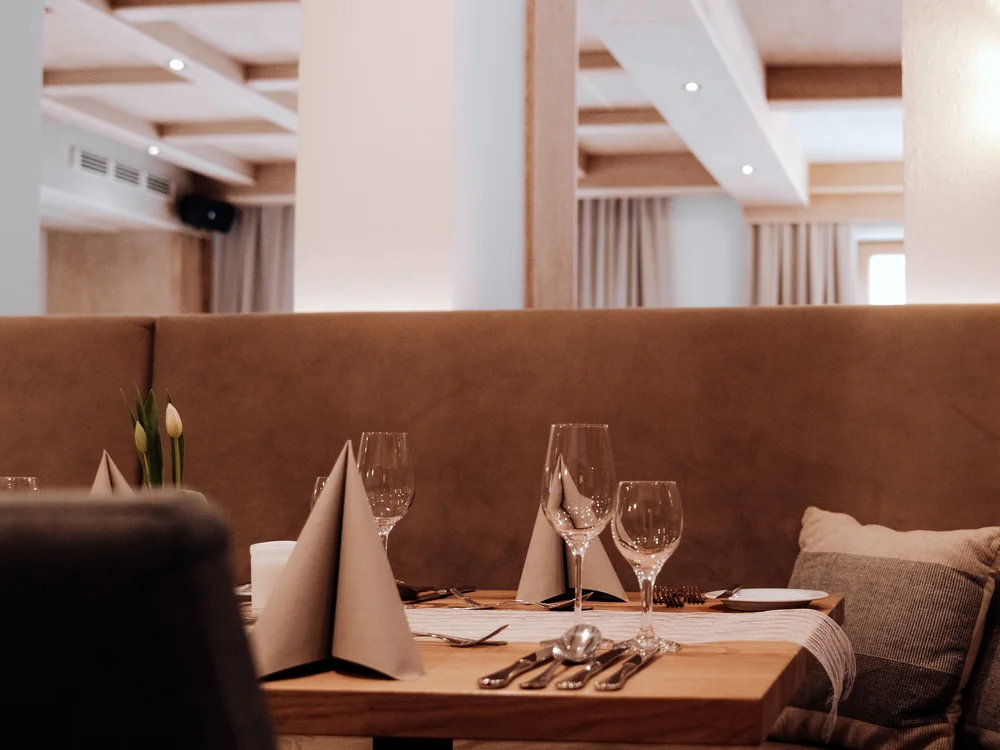 Winterurlaub beim Forstauerwirt Gedeckter Restauranttisch mit Gläsern und gefalteten Servietten in einer gemütlichen Sitznische