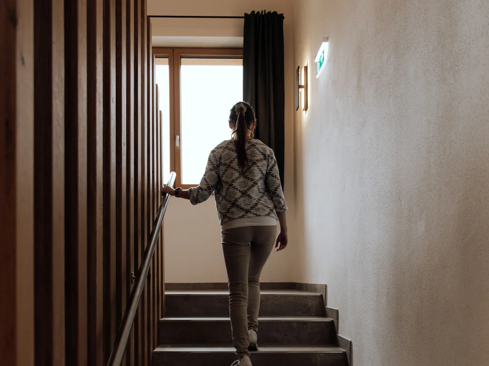Winterurlaub beim Forstauerwirt Eine Frau geht eine Treppe hinauf und hält sich am Geländer fest