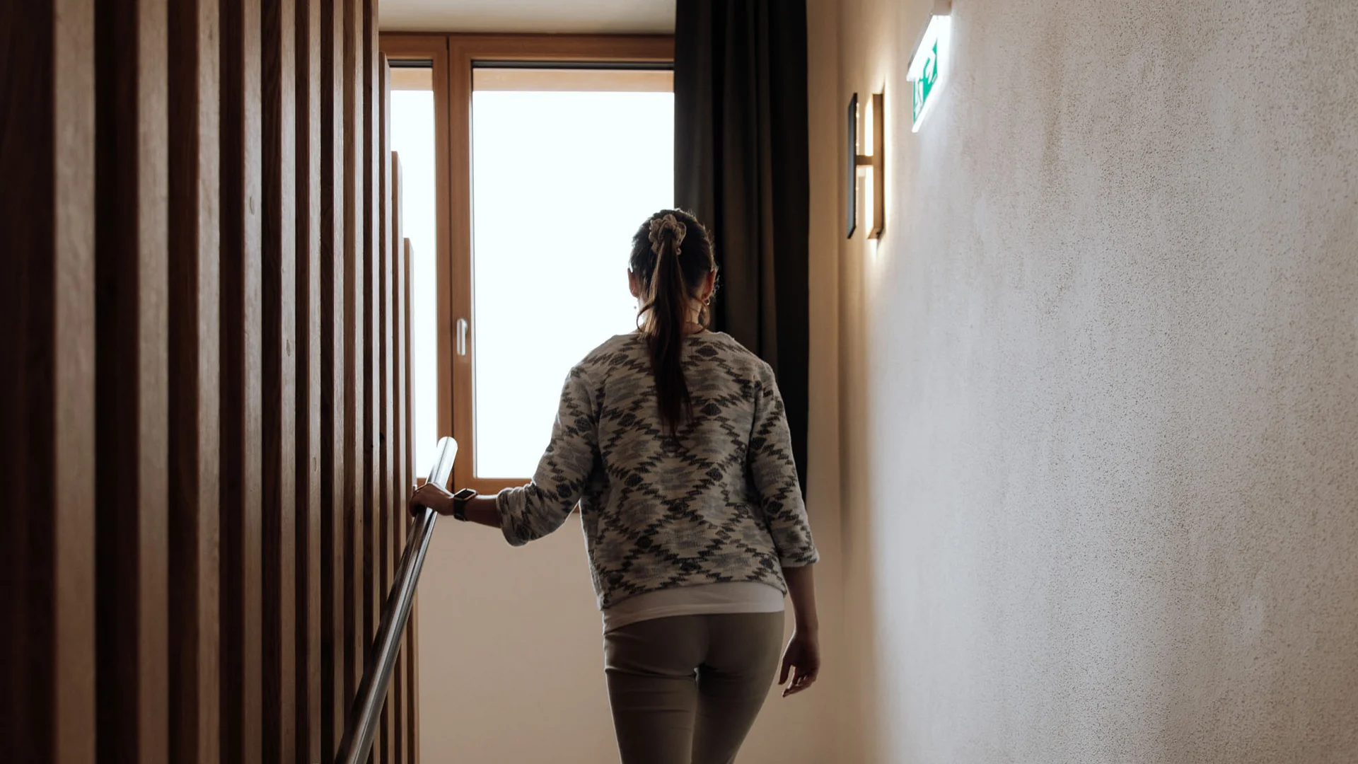 Eine Frau geht eine Treppe hinauf und hält sich am Geländer fest