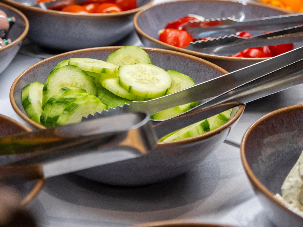 Winterurlaub beim Forstauerwirt Schalen mit Gurkenscheiben und Tomaten an einem Buffet, dazu Servierzangen